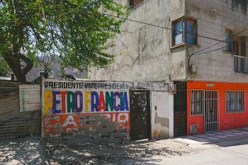 Une image d'une rue et d'un mur coloré avec écrit "Petro Francia" dont la peinture se dégrade.