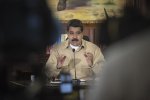 Le président vénézuélien Maduro, de face, assis, qui parle à un micro. 