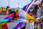Un drapeau LGBTQI+ dans le vent, tenu par une main